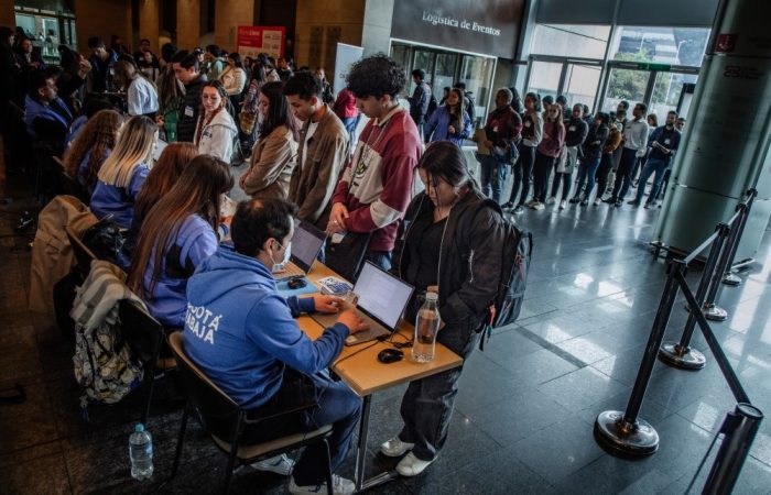 Aparece una mesa en la que un grupo de personas hace fila
