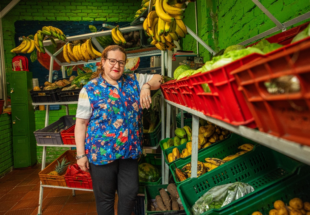 Imagen relacionada con una mujer en su puesto de trabajo, que es una tienda de frutas y verduras