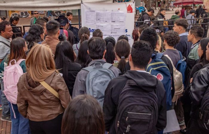 Imagen relacionada con un grupo de personas que revisan listado de vacantes en una feria de empleo