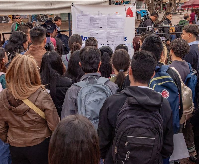 Imagen relacionada con un grupo de personas que revisan listado de vacantes en una feria de empleo