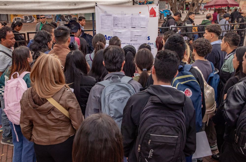 Imagen relacionada con un grupo de personas que revisan listado de vacantes en una feria de empleo