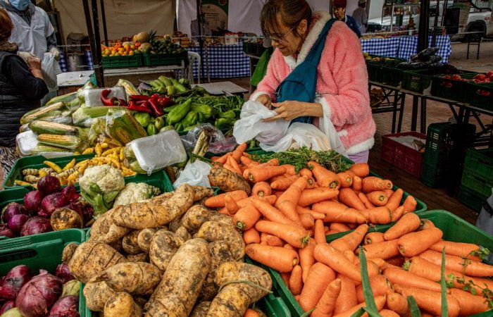 Imagen relacionada con una mujer que compra productos en un mercado campesino