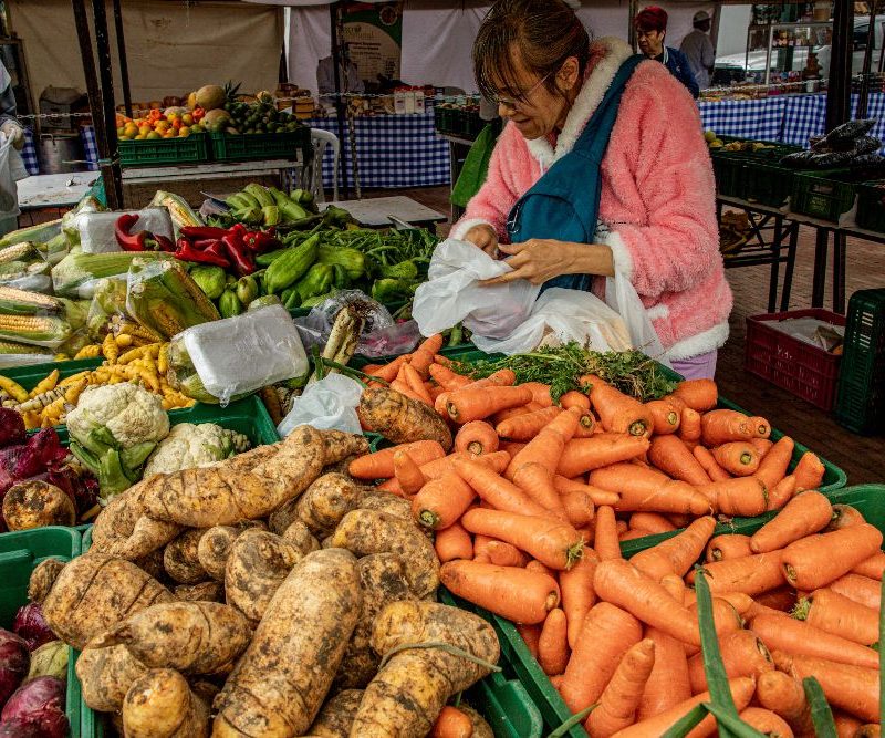 Imagen relacionada con una mujer que compra productos en un mercado campesino