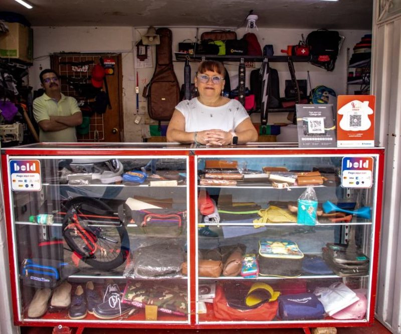 Imagen relacionada con una mujer emprendedora en la entrada de su negocio