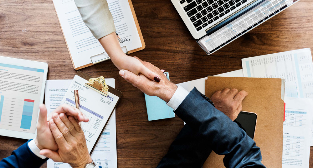 Apretón de manos sobre escritorio con documentos